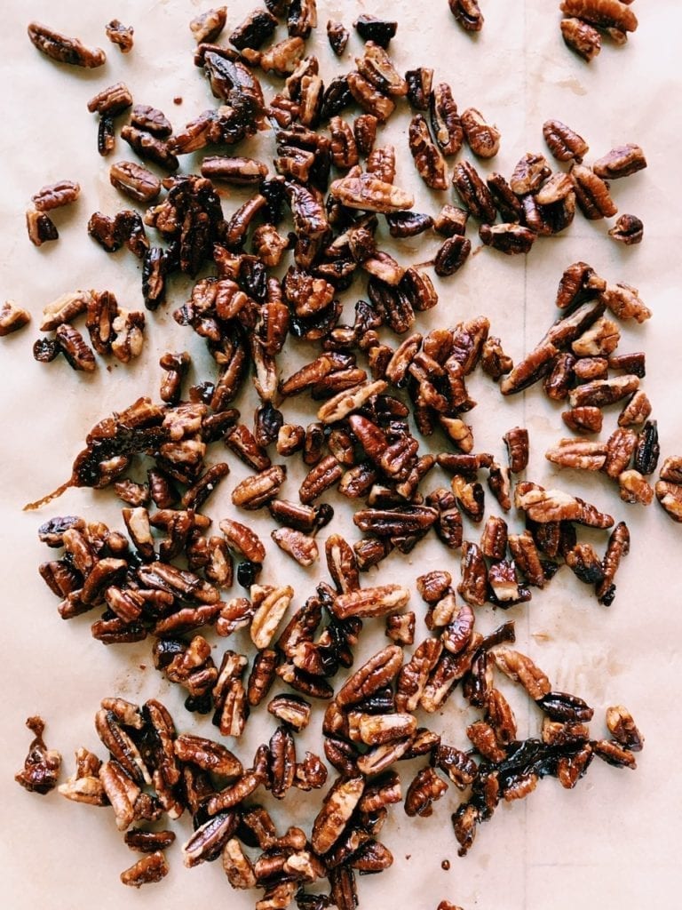 Overhead close up of quick candied pecans on parchment paper.