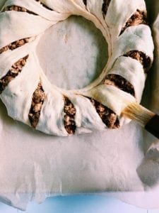 Crescent roll taco ring getting an egg wash before baking