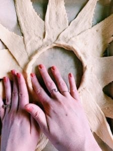 Hands pressing crescent roll dough to form lip around center circle