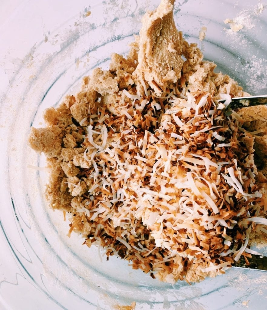 Toasted coconut in bowl with shortbread dough