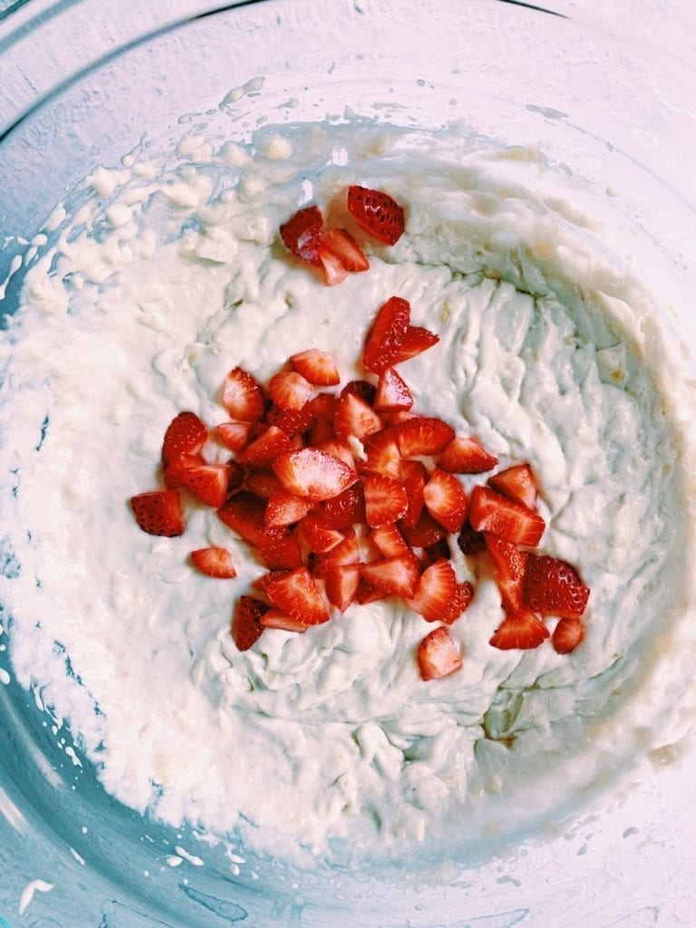 Mashed bananas and coconut milk mixed together in a bowl with strawberries on top. 