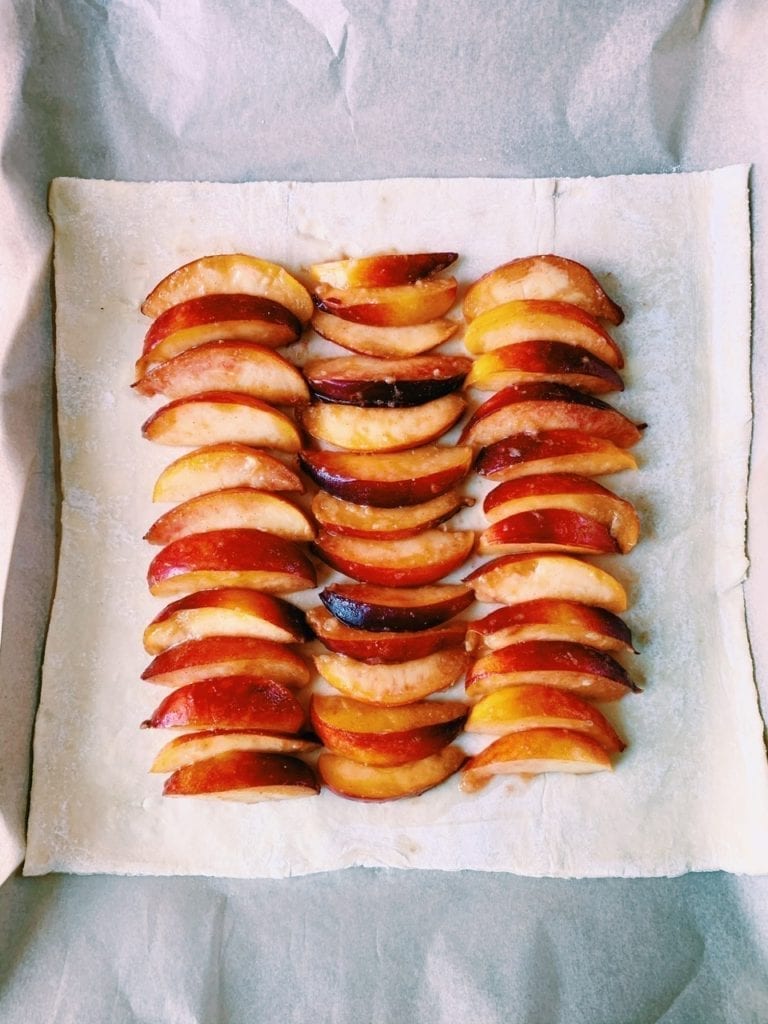Sheet of puff pastry with nectarine slices arrange on top before baking
