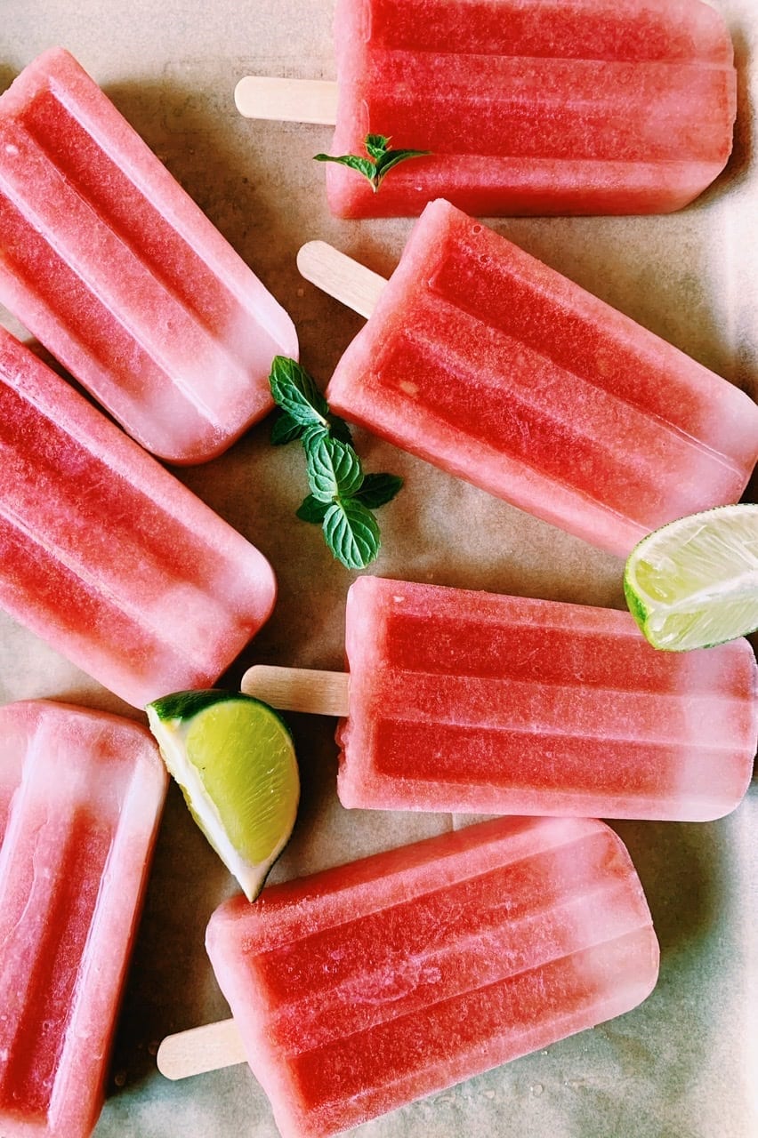 watermelon mint popsicles on a baking sheet with limes and mint