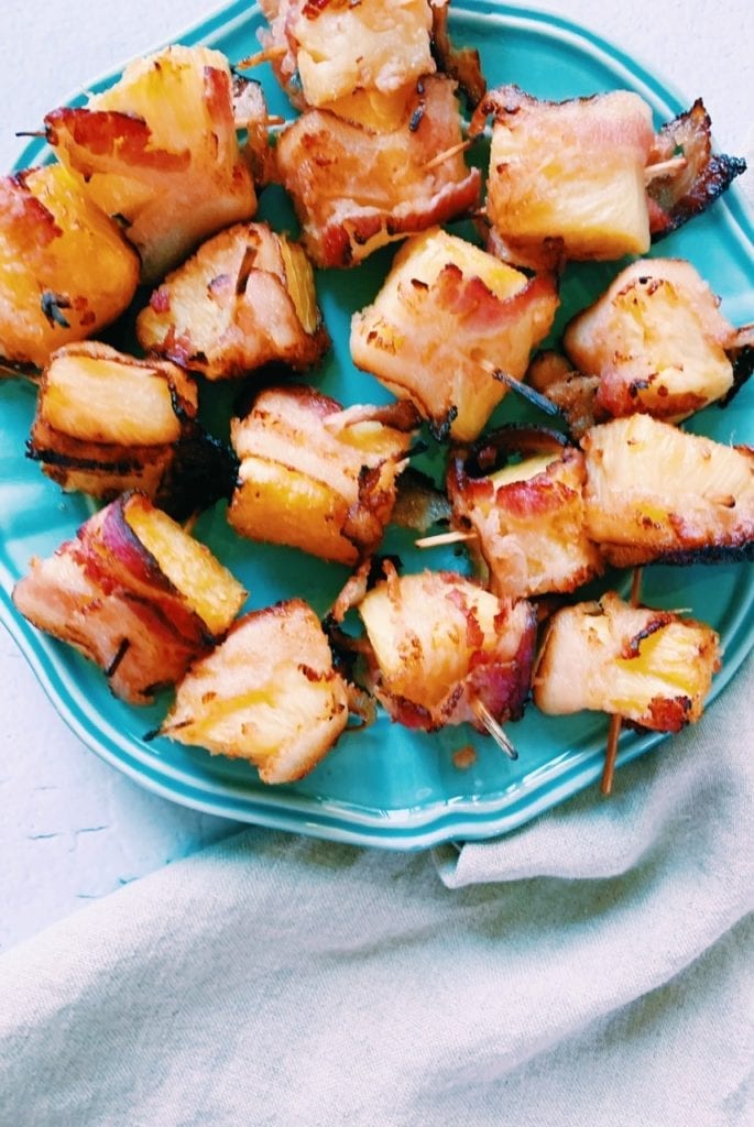 Bacon wrapped pineapple bites on a blue plate for a party