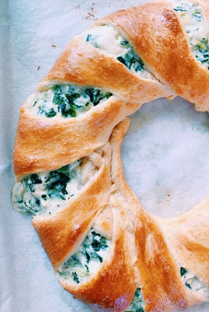 Close up photo of spinach and artichoke dip ring on parchment paper