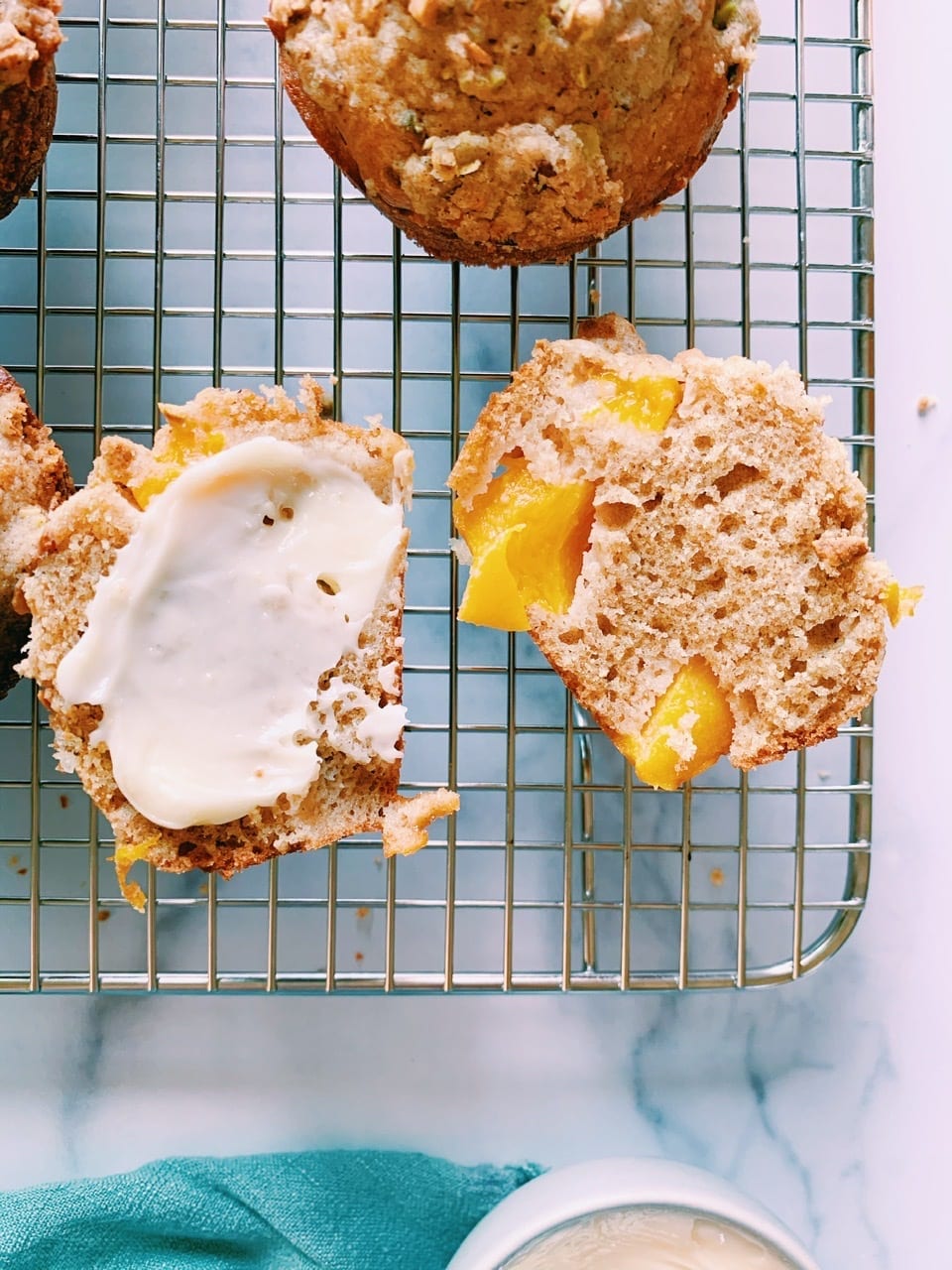 Close up of peach cardamom muffin with pistachio crumble cut in half on cooling rack