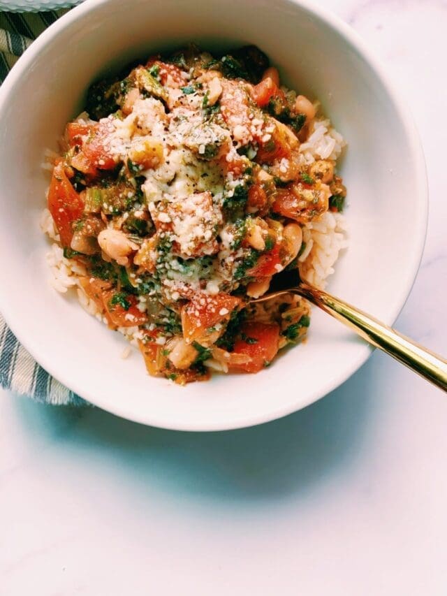 Instant white bean, tomato and spinach stew in a white bowl with a gold spoon