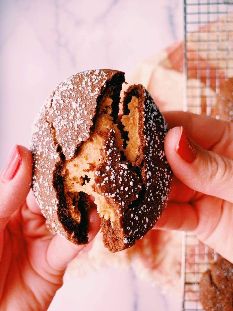 Peanut butter filled chocolate cookie being broken in half to revel creamy peanut butter center