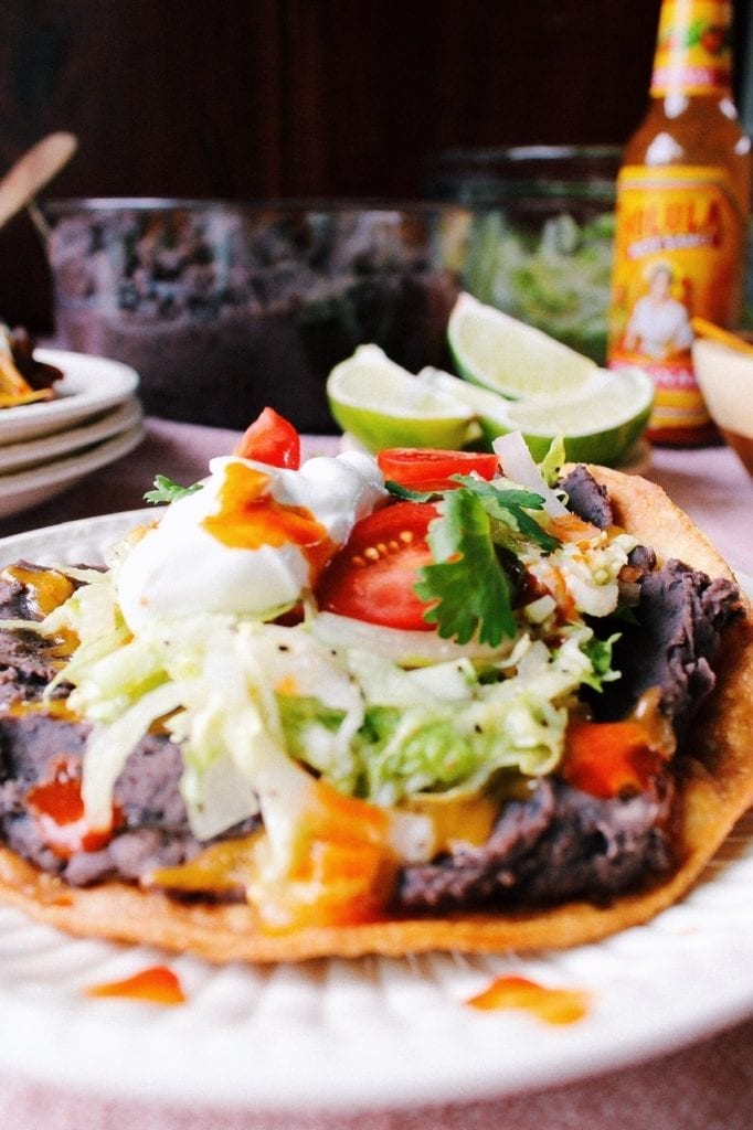 Straight on view of homemade tostadas with refried black beans on a white plate. 