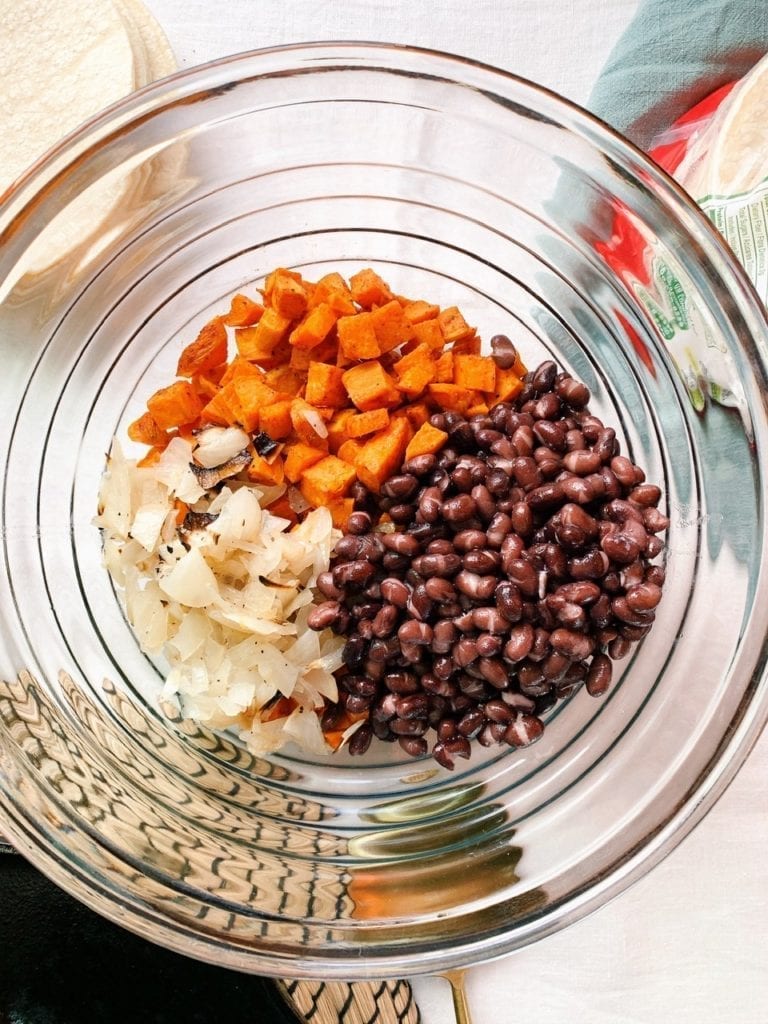 Sweet potatoes, black beans and onions in a mixing bowl. 