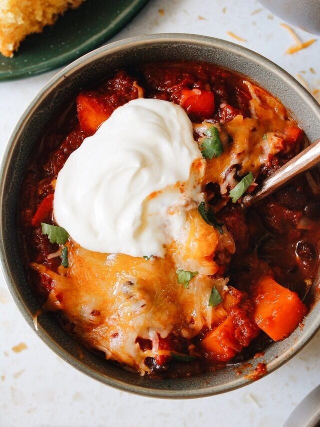 Close up of thick and heart sweet potato black bean chili topped with sour cream and cilantro