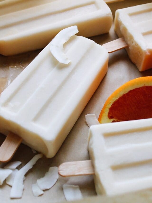 orange coconut milk popsicles with orange slices and coconut shreds