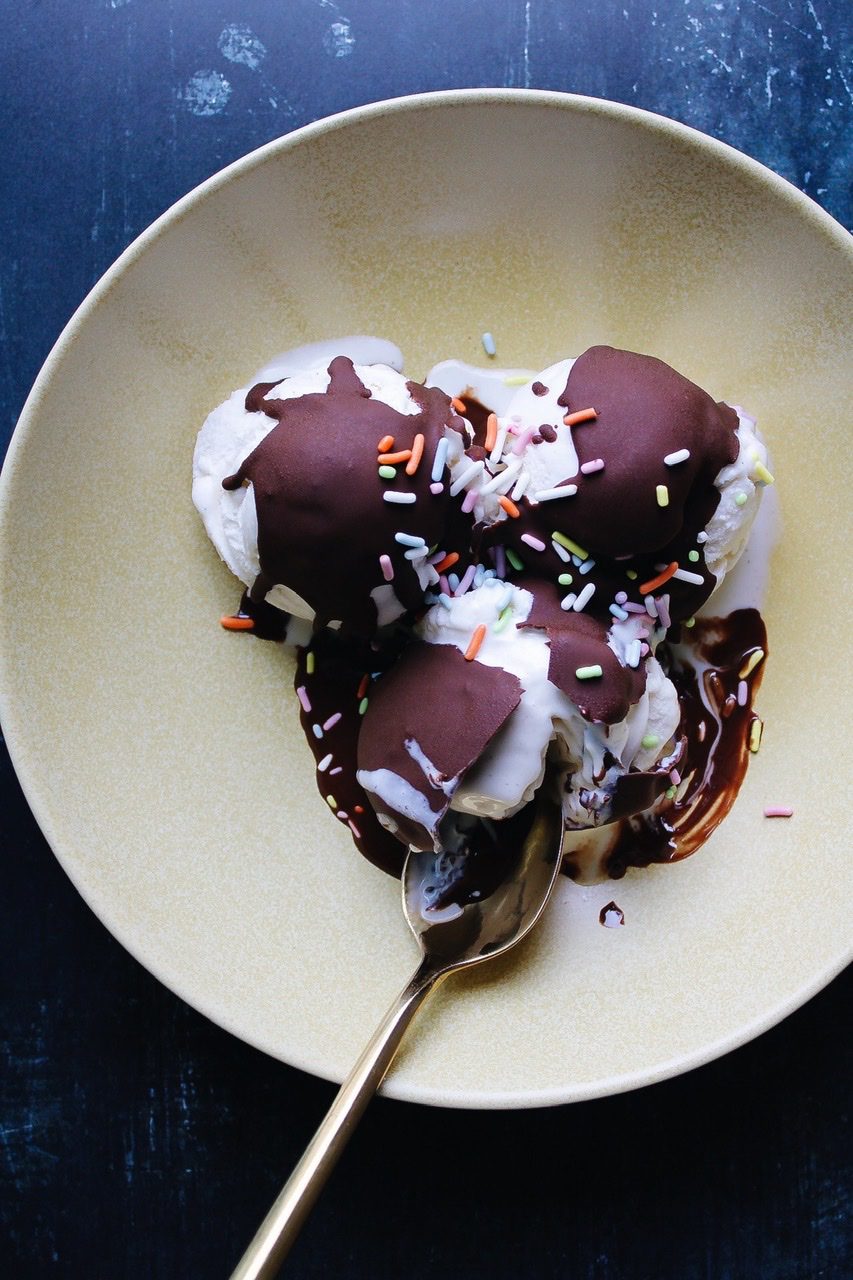 overhead shot of a bowl of vanilla icecream with chocolate shell ice cream topping