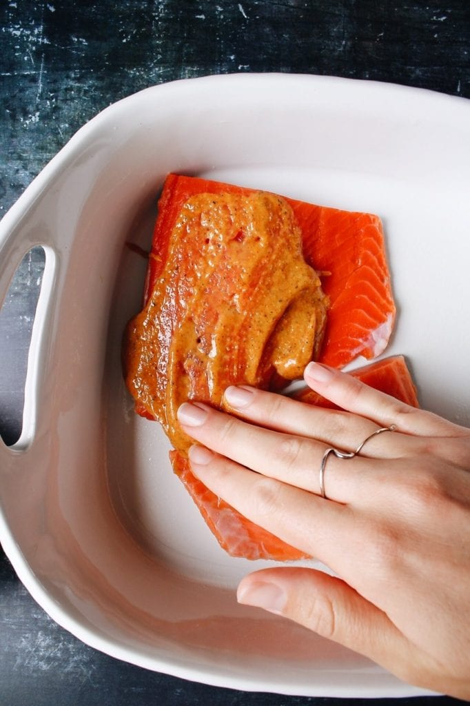 honey mustard marinade being rubbed into salmon