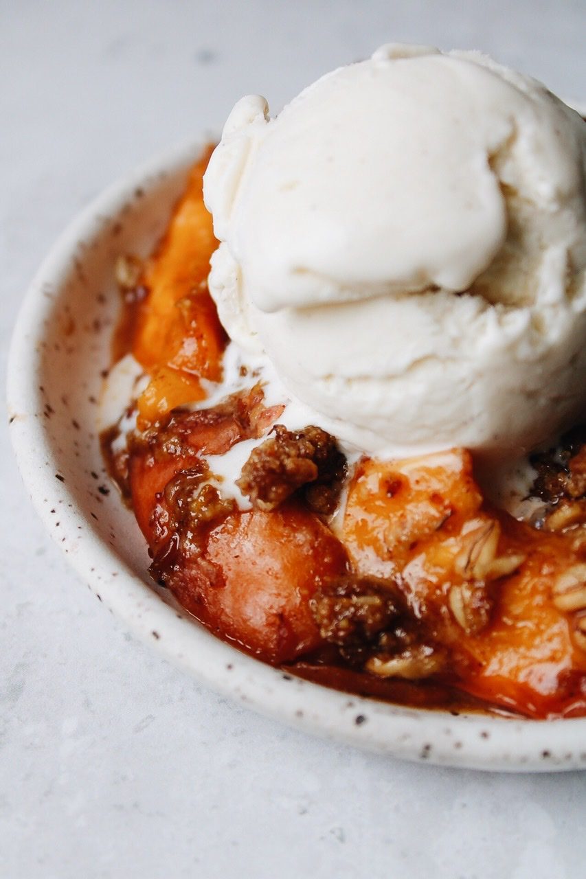 rhubarb and nectarine crumble with ice cream on a speckled plate