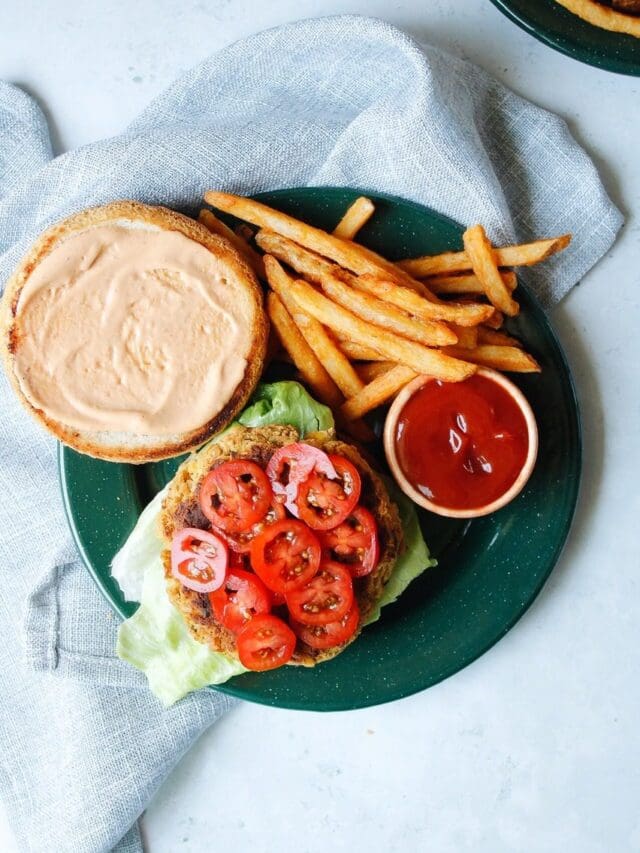 open faced chickpea burger on a green plate with french fries