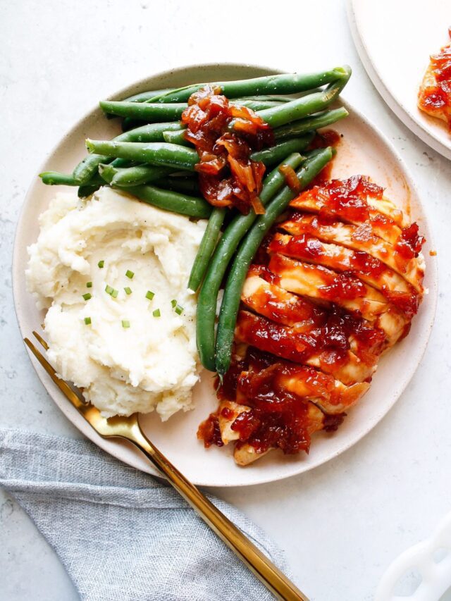 baked saucy chicken on a plate with mashed potatoes and green beans