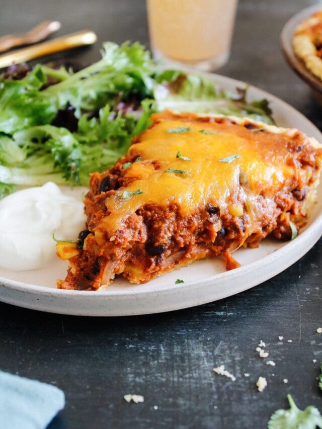 side view of tamale pie on a plate with a mixed green salad