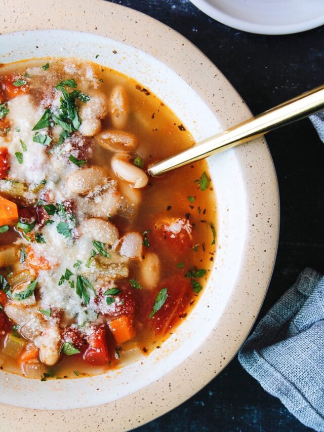 vegetable bean soup in a beige bowl with a gold spoon