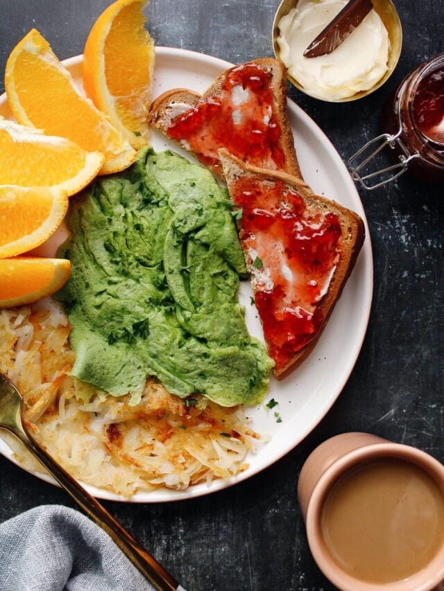 overhead shot of spinach eggs on a plated with fruit, toast and hashbrowns.