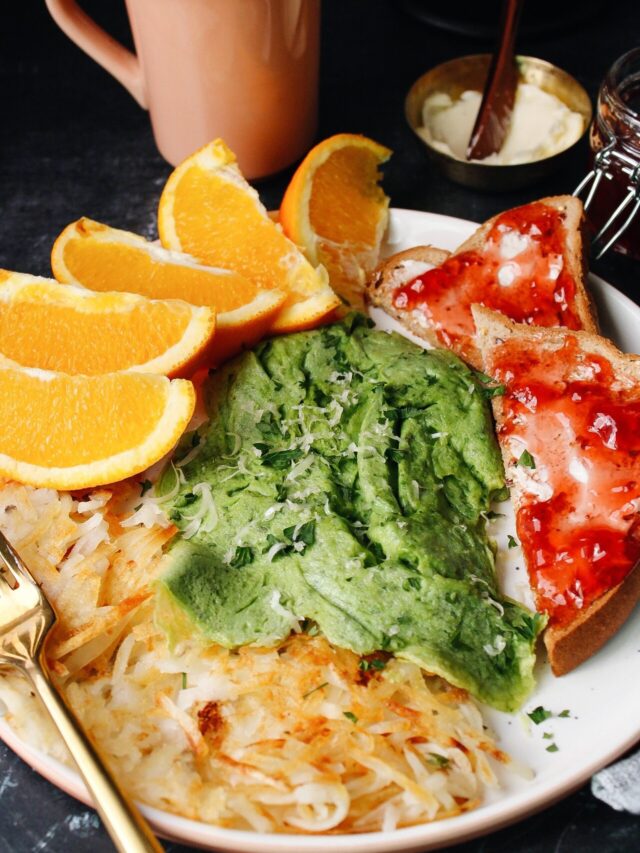 spinach eggs on a plated with hashbrowns, oranges and toast