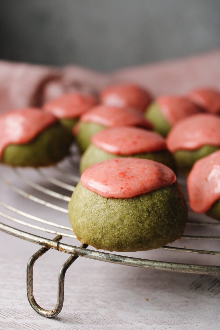 matcha shortbread cookies with strawberry icing on an antique cooling rack