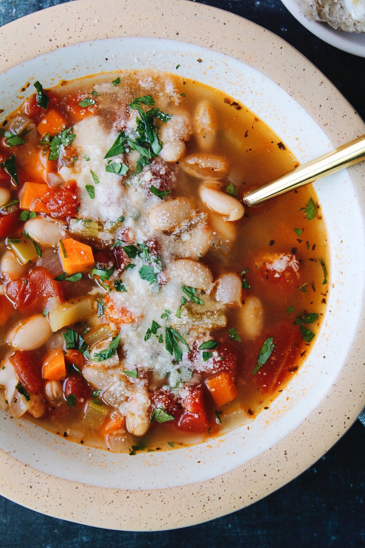 close up of vegetable bean soup in a beige bowl