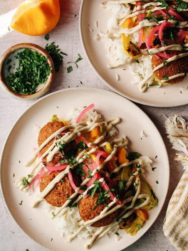 trader joes falafel on plates with rice, veggies, tahini lemon garlic sauce and pickled onions