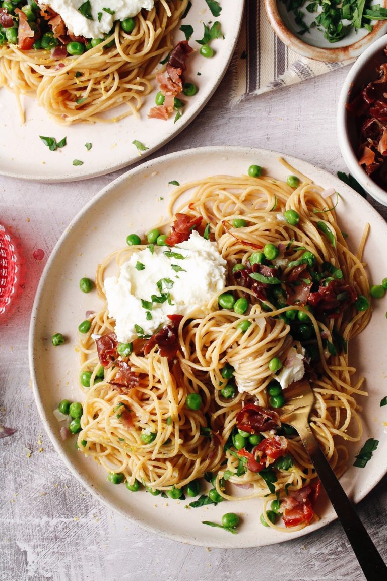 pasta with peas and prosciutto on beige plates with wine and extra toppings