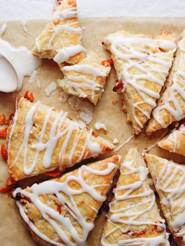 roasted kumquat scones on a baking sheet with a spoon of icing