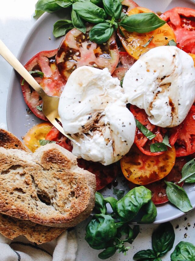 caprese salad with burrata cheese on a gray plate