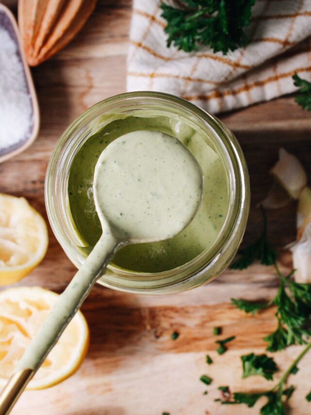 Lemon herb tahini sauce on a spoon resting over a jar