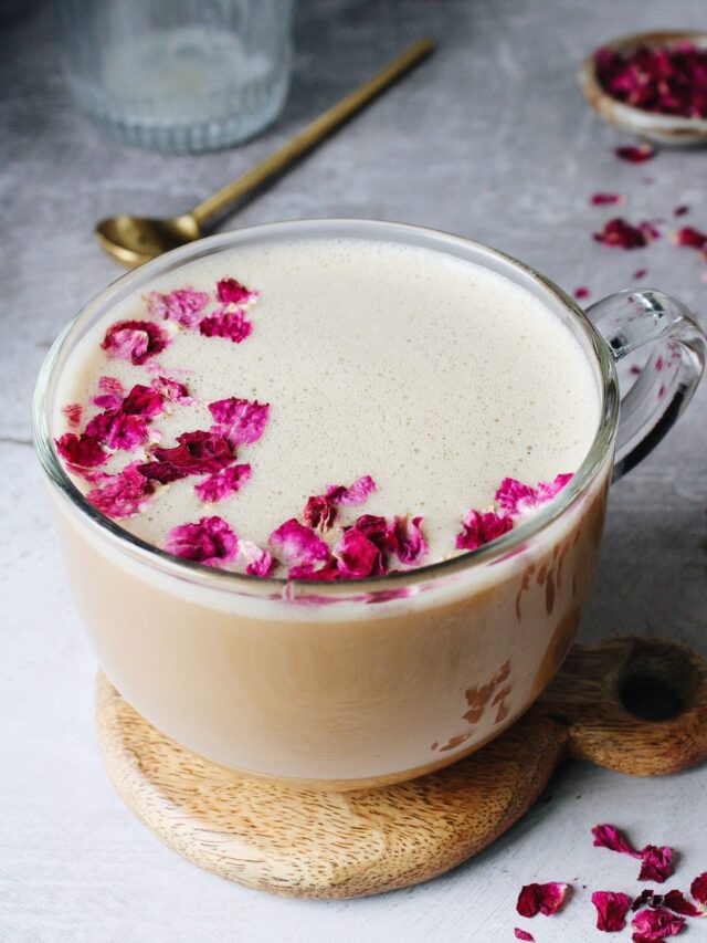 rose latte in a glass mug topped with dried rose petals