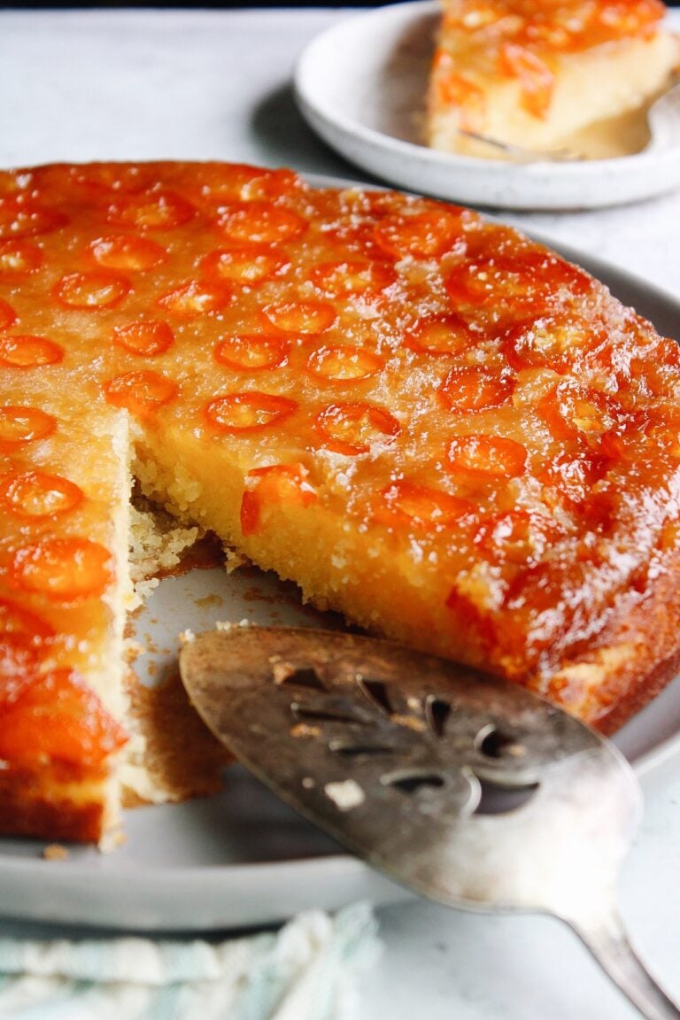 kumquat upside down cake on a gray plate with a cake server resting on the plate