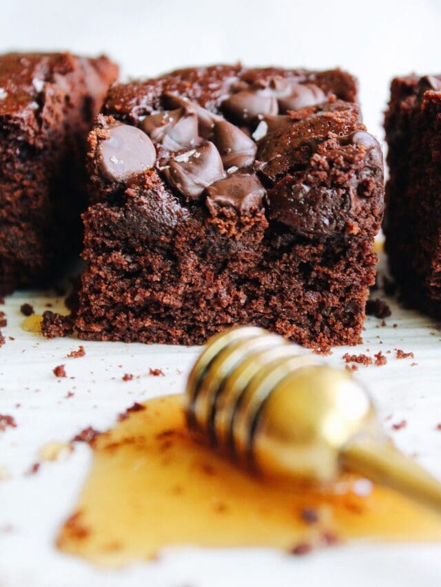 close up of honey brownies with a honey dipper in the foreground