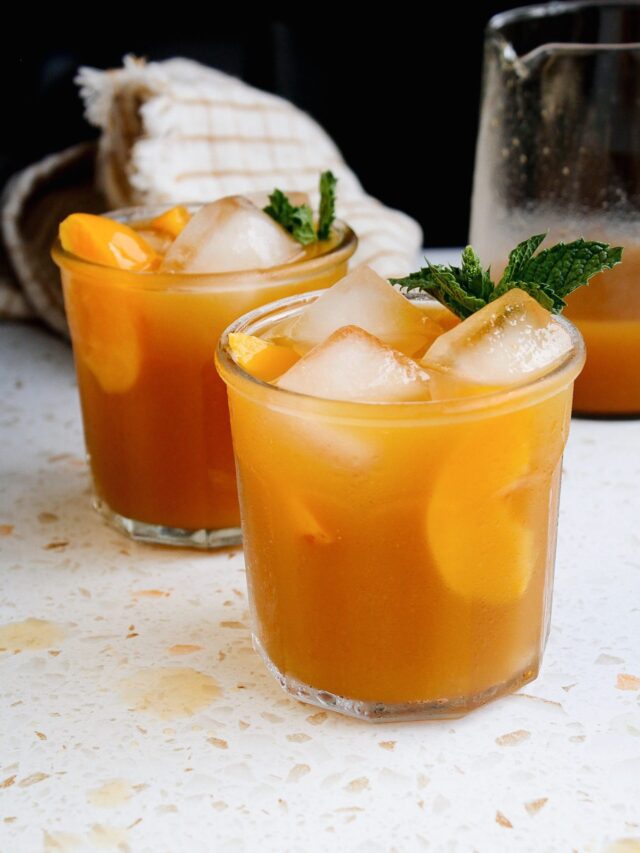 peach iced green tea in a clear glass with peach slices and mint