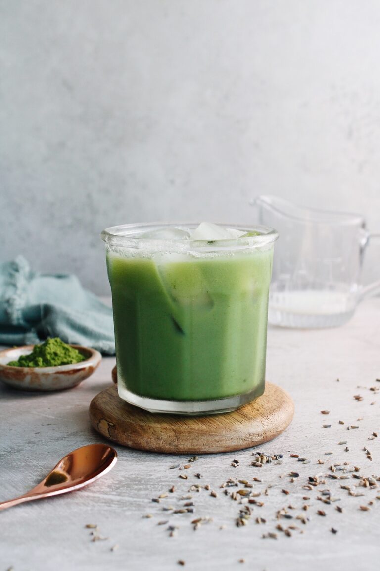 lavender matcha latte in a clear glass over ice