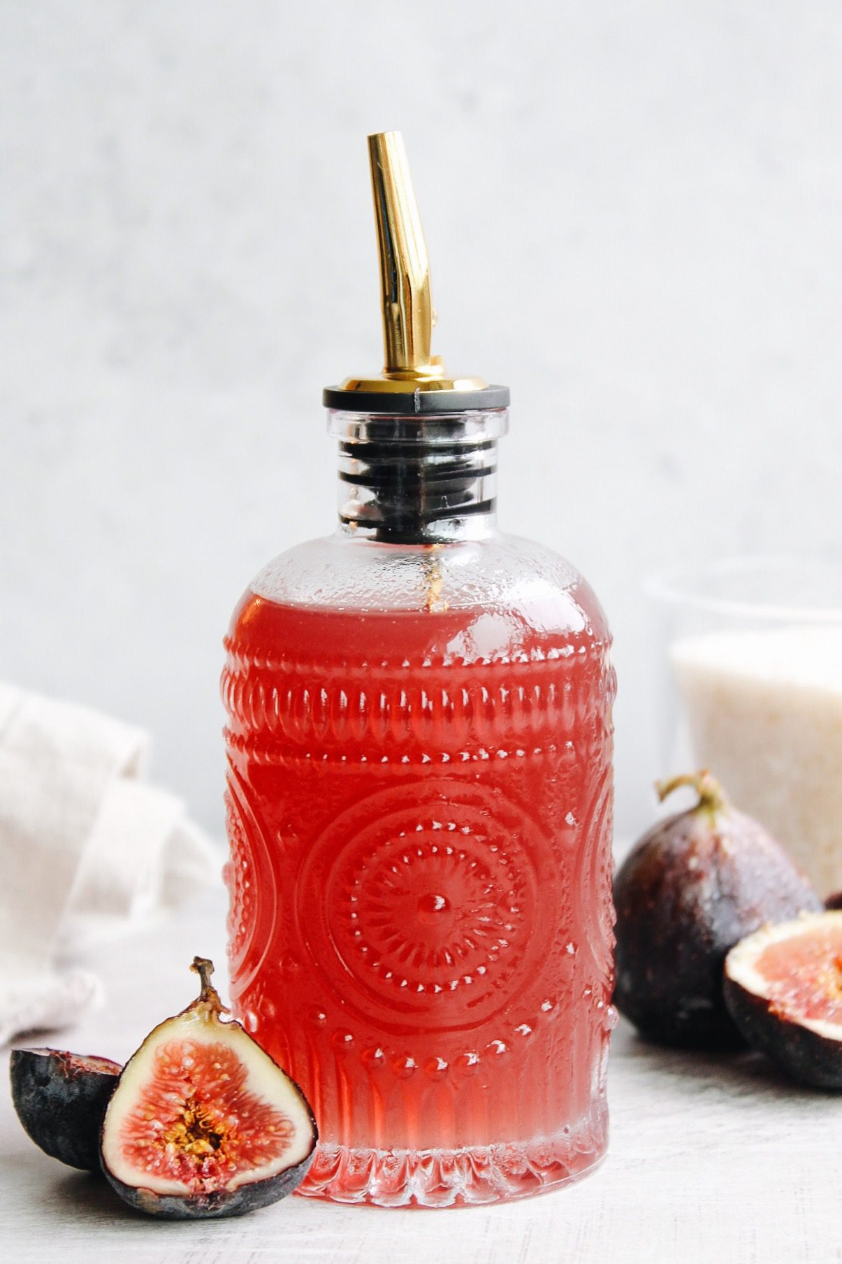 fig syrup in a glass syrup bottle with figs scattered around