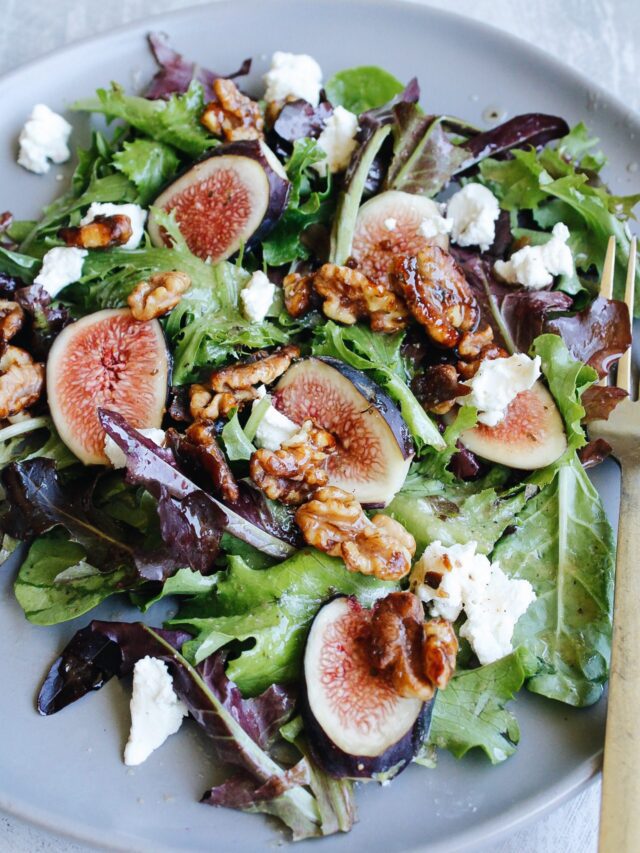 fig salad with goat cheese, candied walnuts and vinaigrette on a gray plate