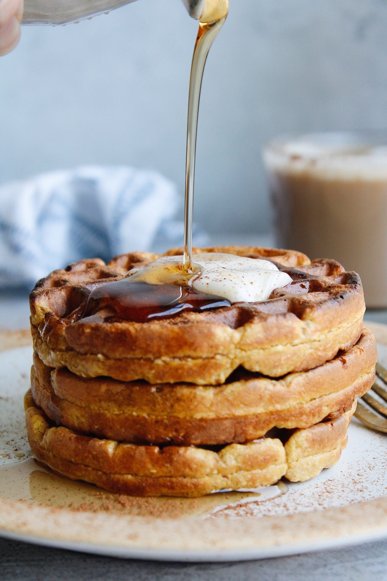 close up of gf pumpkin waffles topped with butter and syrup being drizzled on top