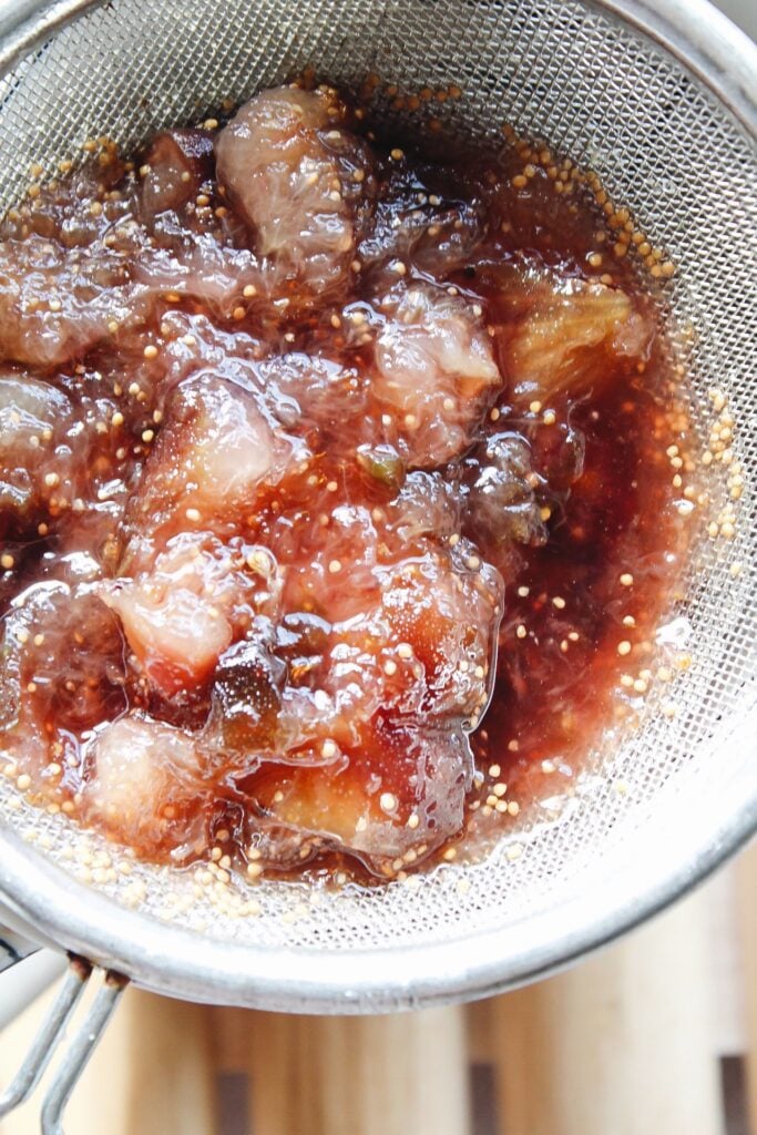 fig syrup being placed in a fine mesh sieve