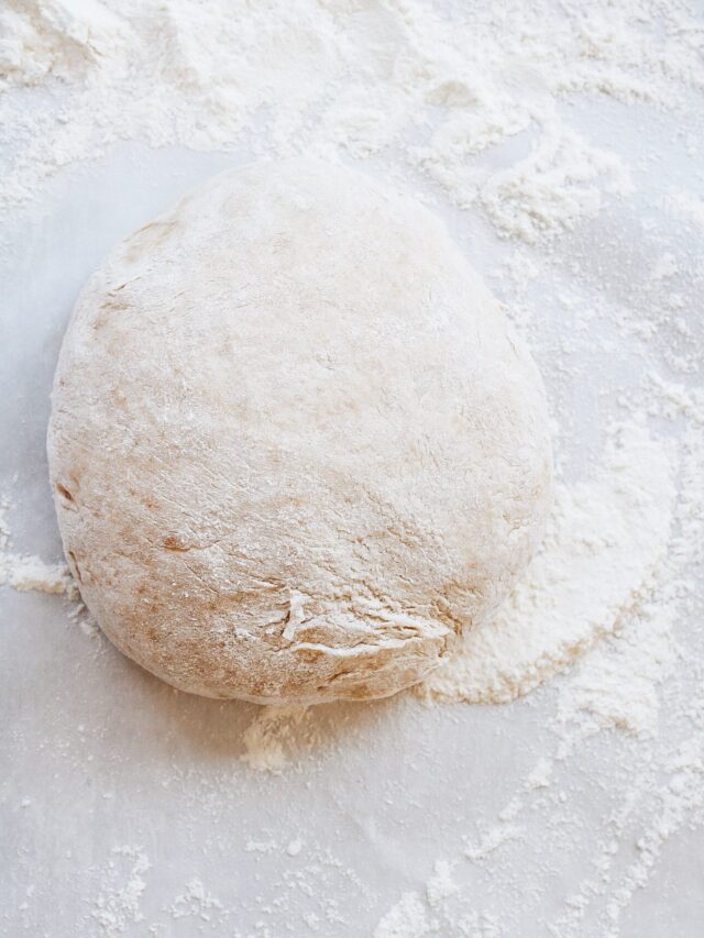 ball of homemade pizza dough on a floured surface