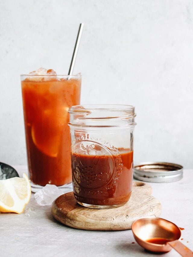 black tea concentrate in a small glass jar with a glass of iced tea behind it