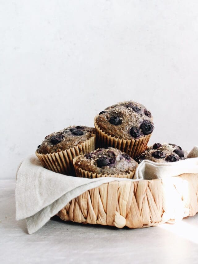 blueberry buckwheat muffins in a strawbasket with a ray of sub hitting it