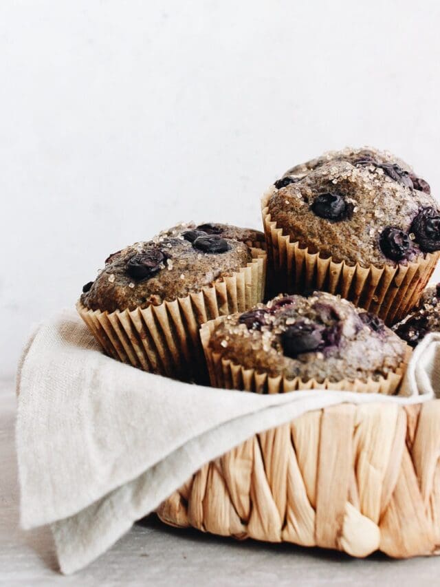 blueberry buckwheat muffins stacked in a straw basket