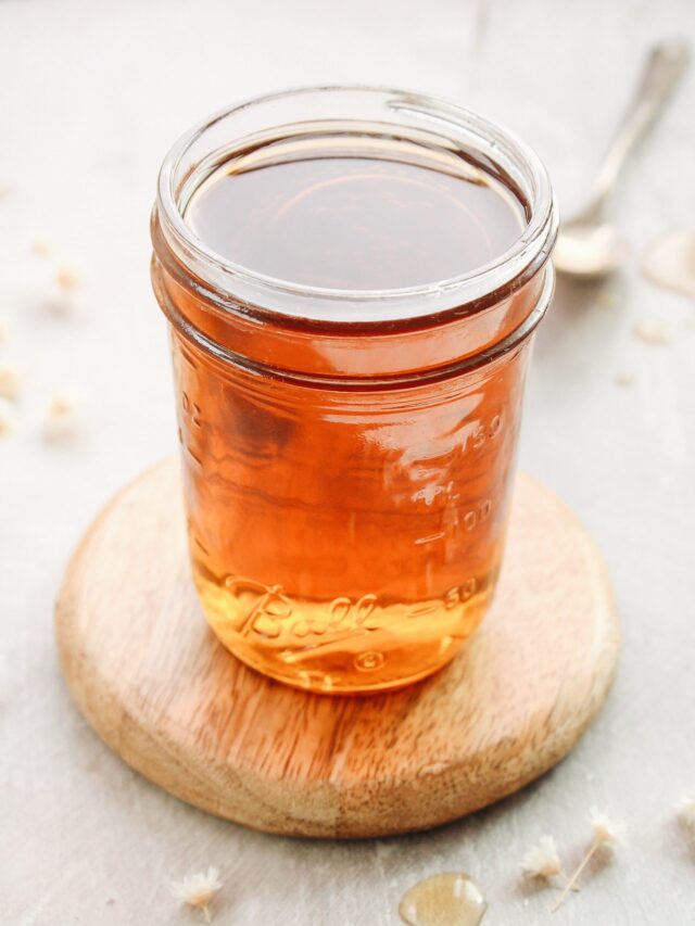 chamomile syrup in a glass jar on a wooden coaster