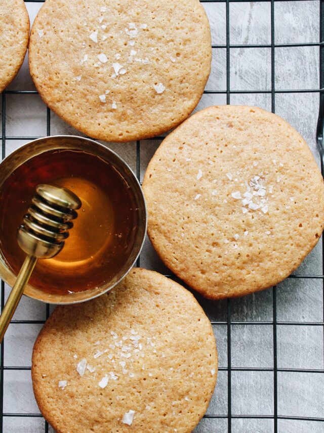 honey cookies with sea salt on a black wire cooling rack with a dish of honey