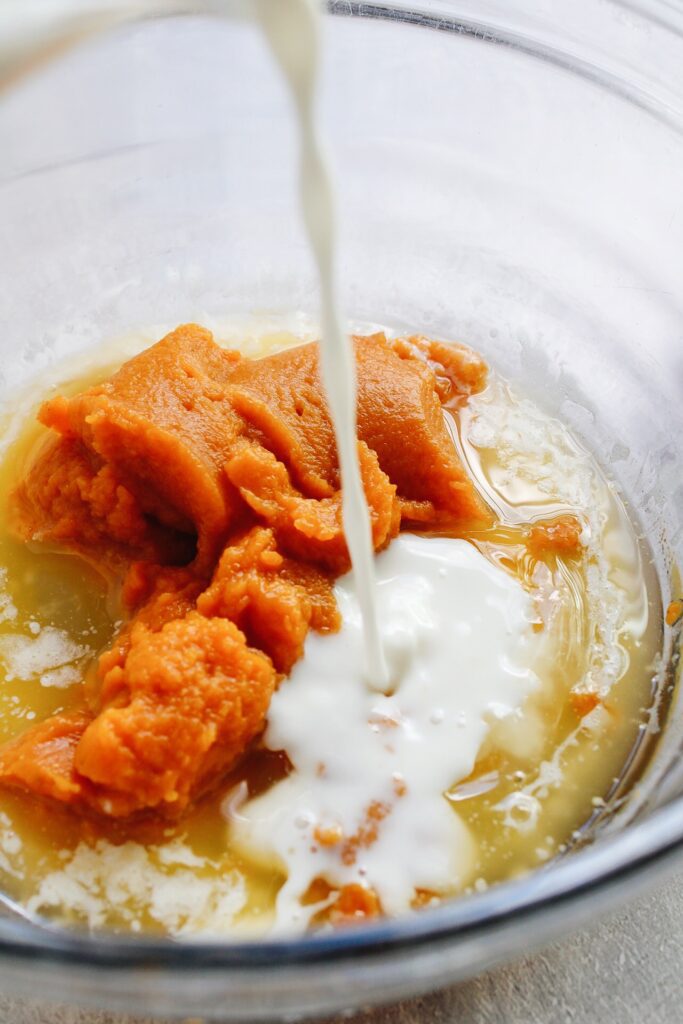 milk being poured into mixing bowl with other wet ingredients for buckwheat pumpkin muffins