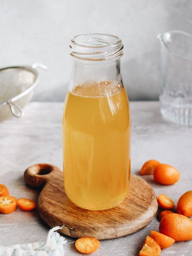 kumquat syrup in a glass jar on a wooden coaster