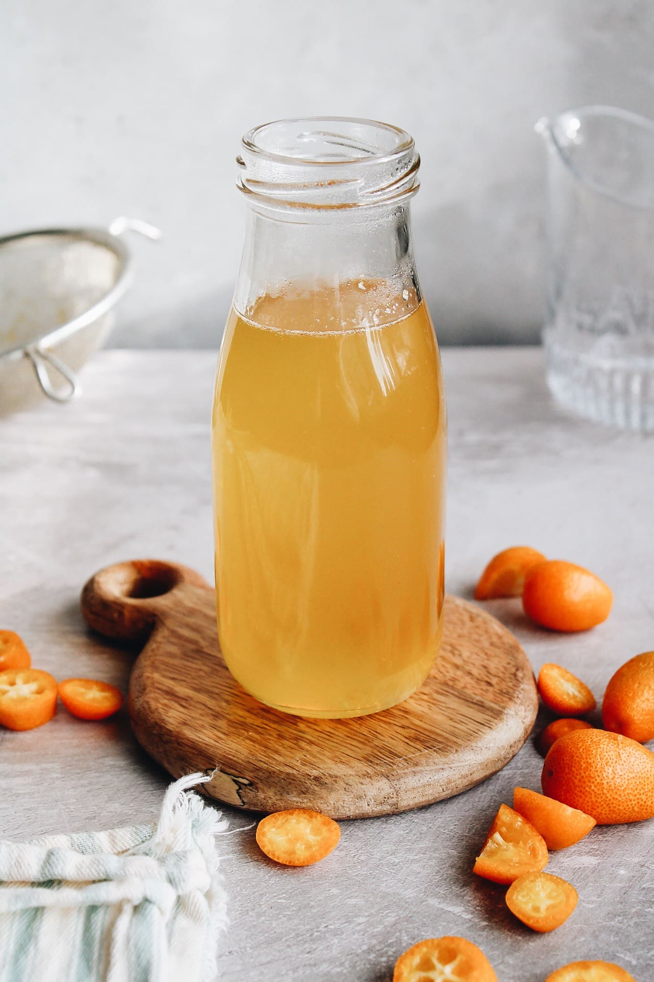 kumquat syrup in a glass jar on a wooden coaster